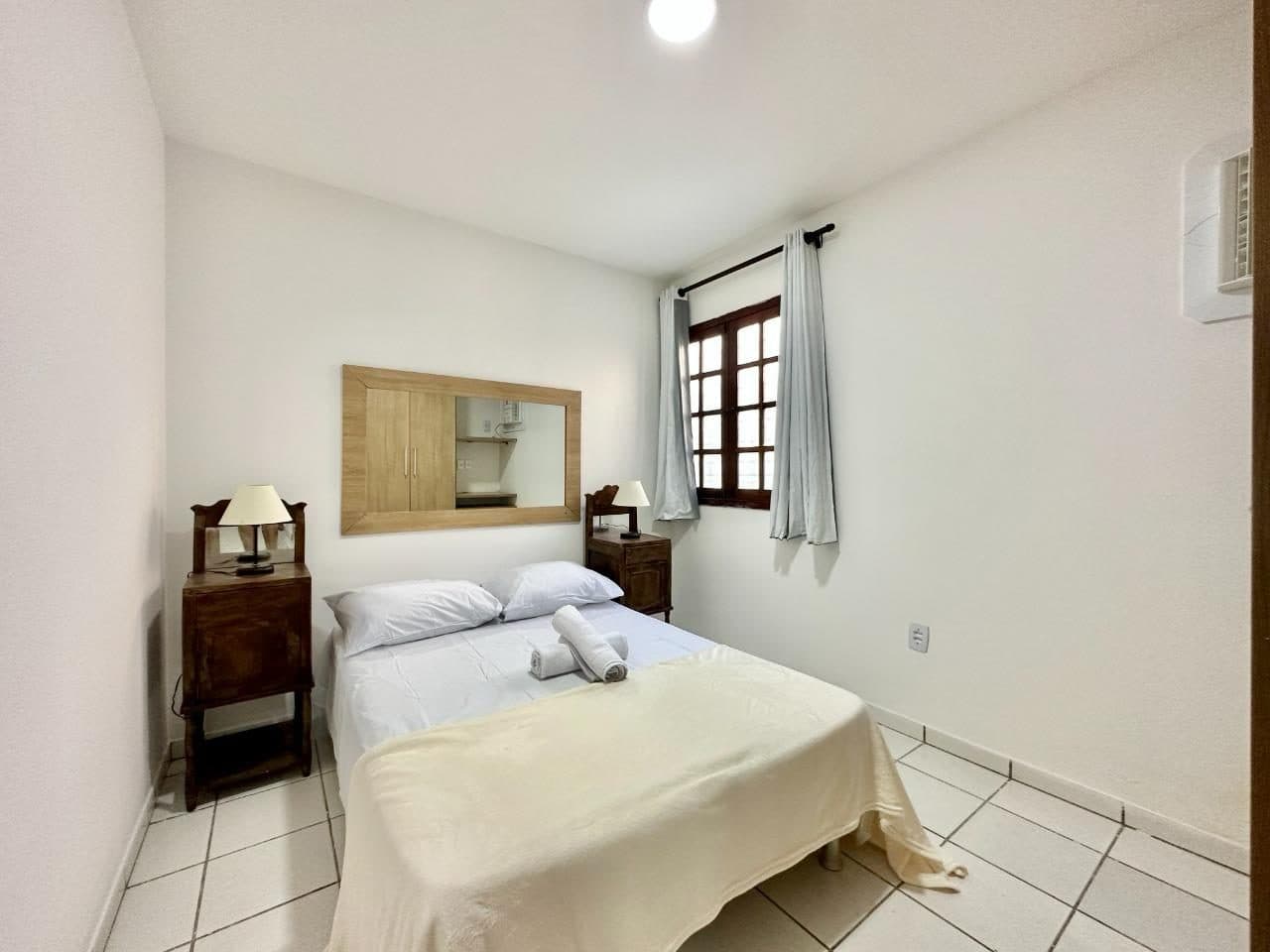 Quarto com cama de casal, criados-mudos e janela