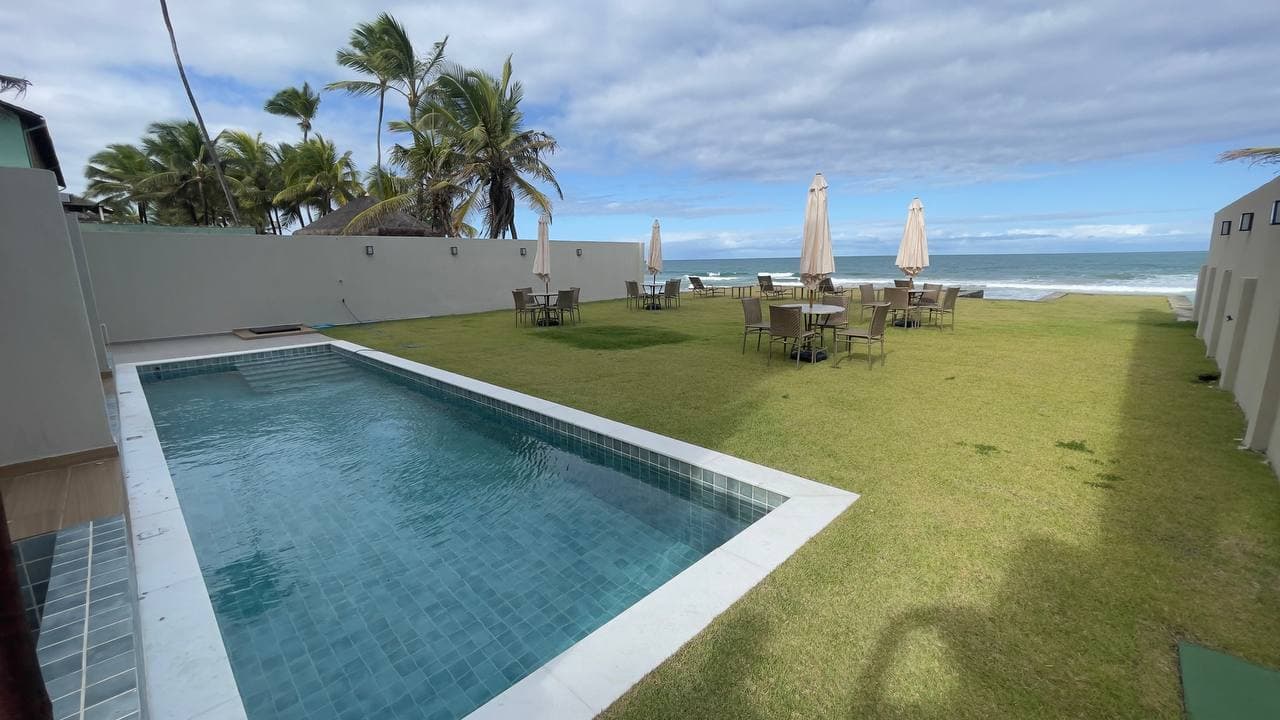 Piscina com gramado de frente para o mar